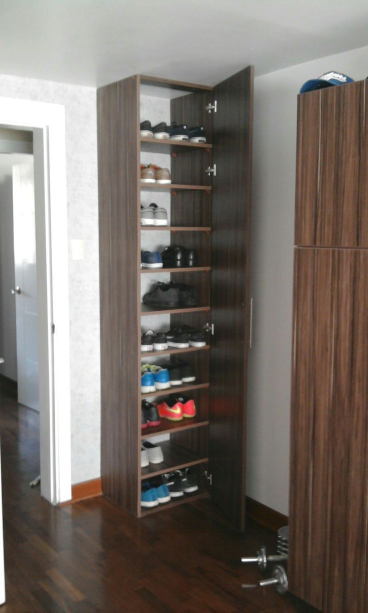 an empty room with wooden floors and shelving unit in the corner, filled with shoes