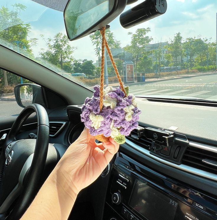 a person holding flowers in their hand while driving