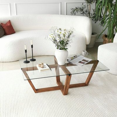 a living room with white couches and a glass coffee table in the center area