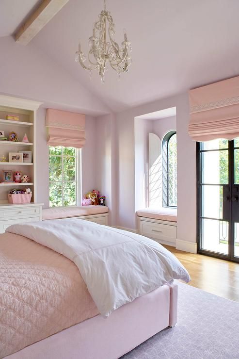 a bedroom with pink walls, white bedding and chandelier hanging from the ceiling