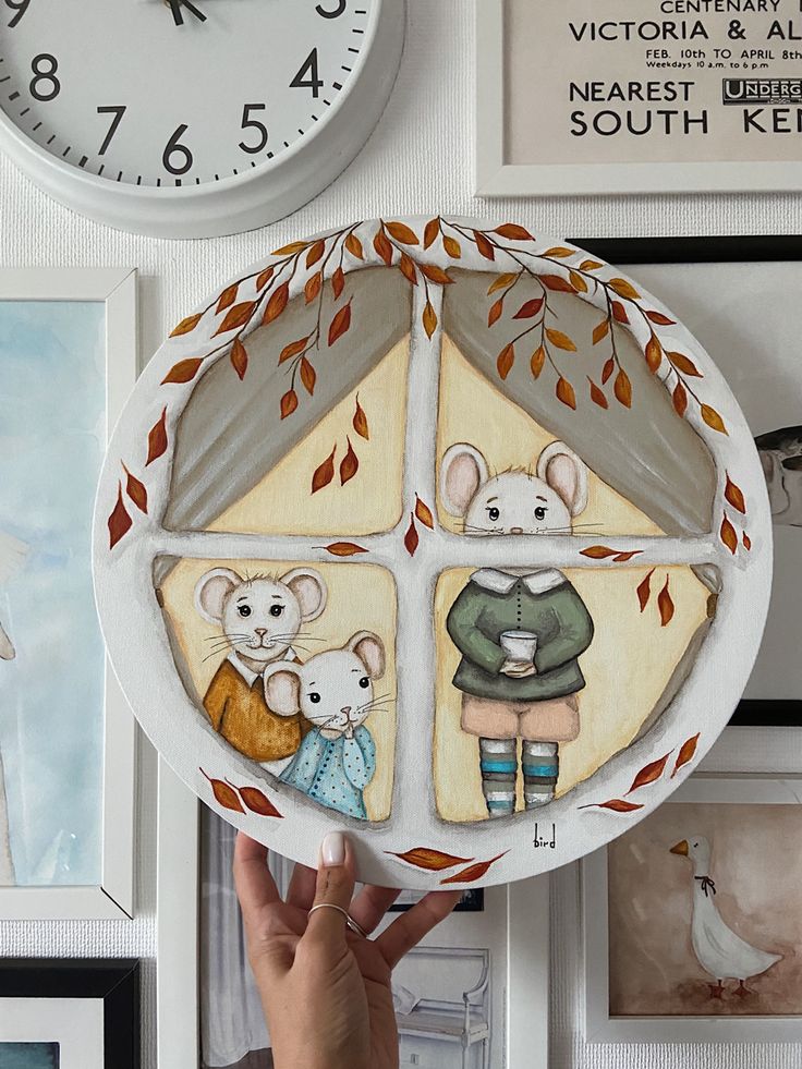 a hand is holding up a plate with pictures on it and a clock in the background