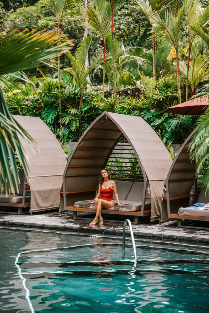 a woman sitting on the edge of a swimming pool with text overlay reading top things to do in la fortuna costa rica