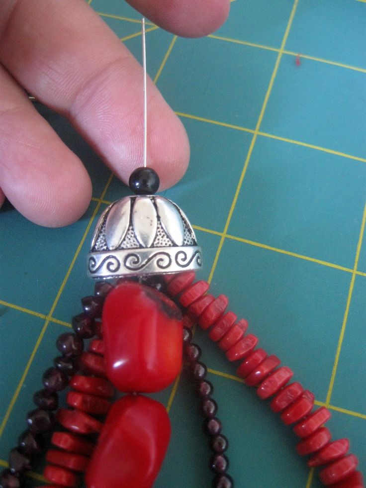 a person is making beaded necklaces with red beads