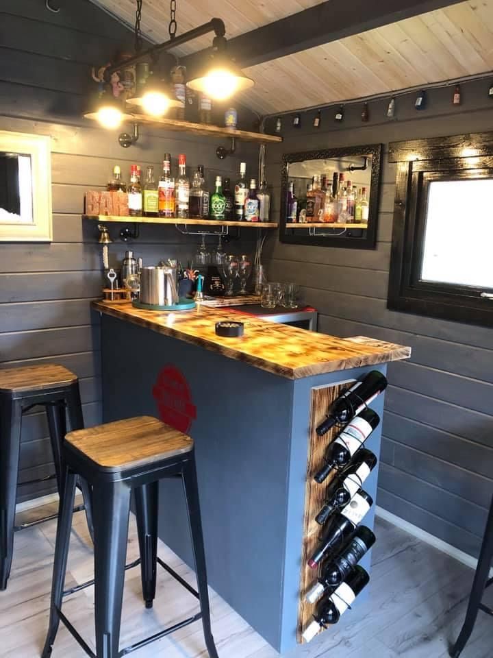 a bar with two stools in front of it and bottles on the counter top