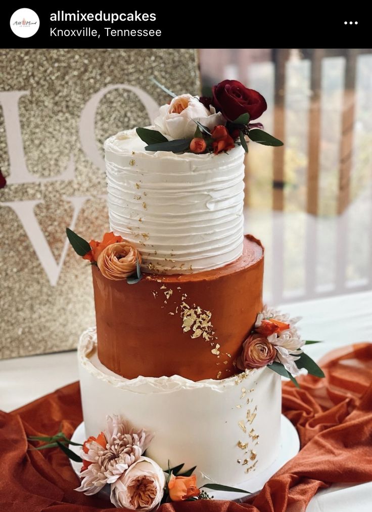 a three tiered wedding cake with flowers on the top and bottom is white, brown, and orange