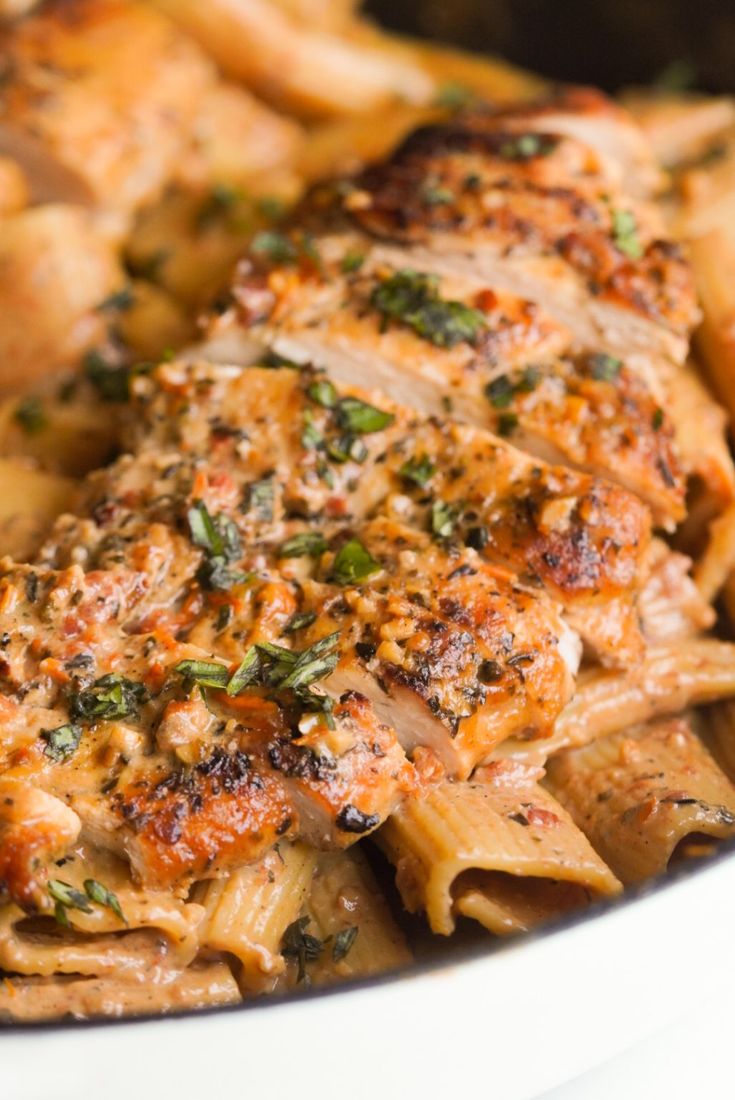 a close up of food on a plate with pasta and meat in sauce, garnished with parsley