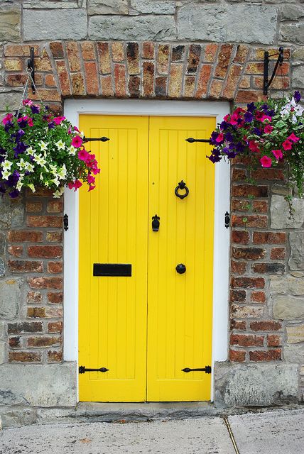 two yellow doors with flower boxes on each side and one door is painted bright yellow