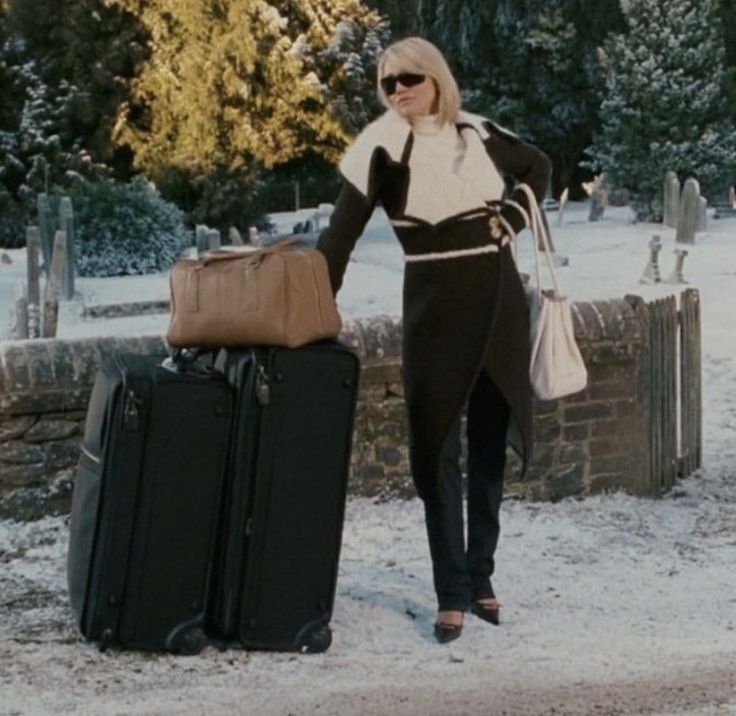 a woman standing next to two suitcases in the snow