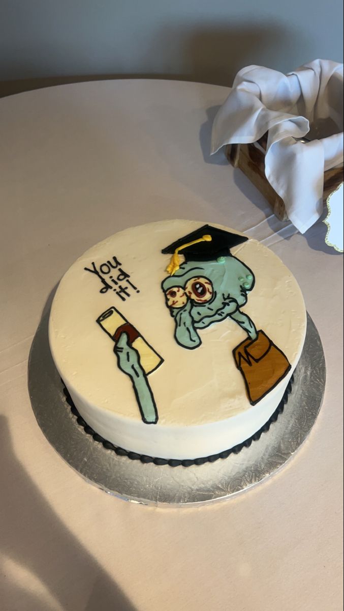 a cake decorated with an image of a zombie holding a book and wearing a graduation cap