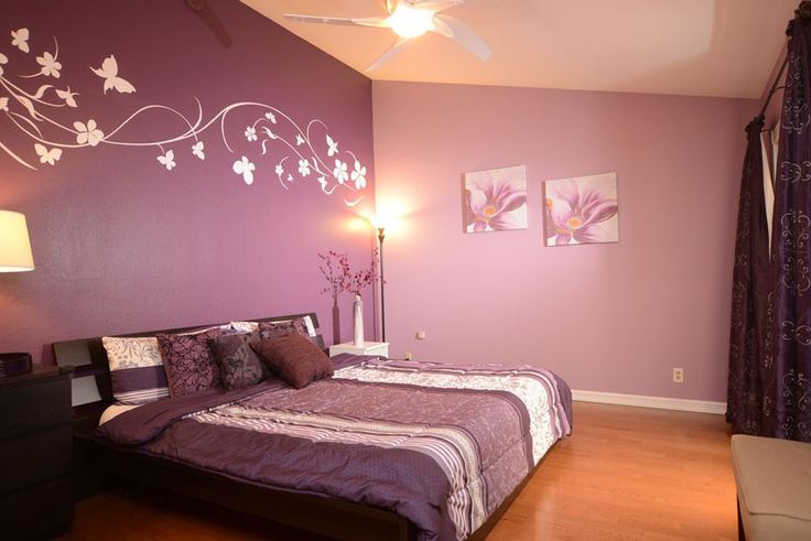 a bed room with a neatly made bed and purple walls