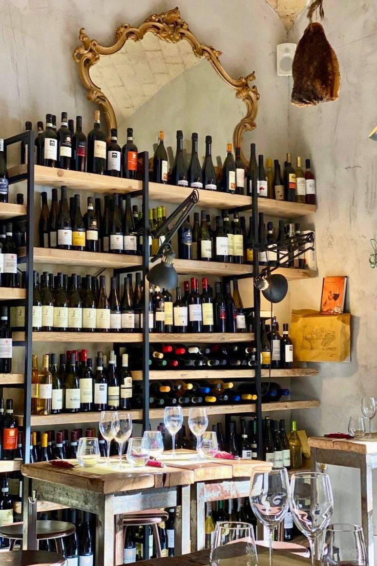 a room filled with lots of bottles and glasses on top of wooden tables next to a mirror