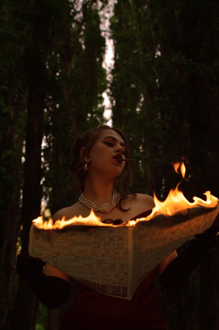 a woman holding a book with flames in her hands