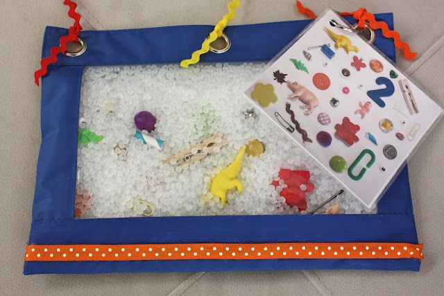 a child's play mat with toys in it on top of white carpeted floor