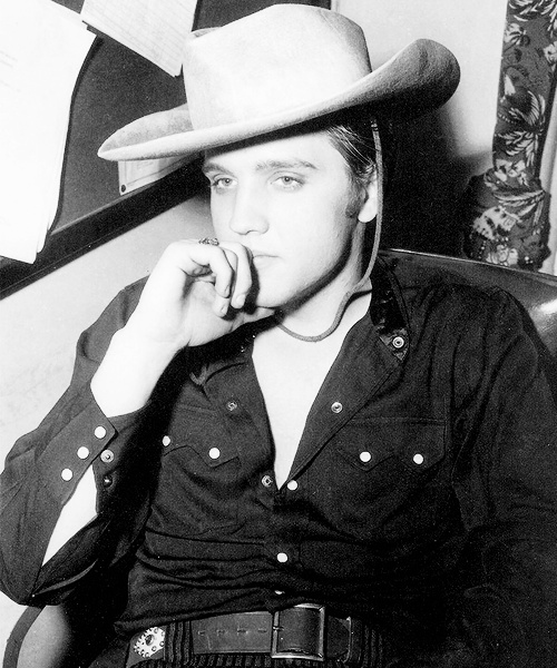 black and white photograph of a man wearing a cowboy hat with his hand to his mouth