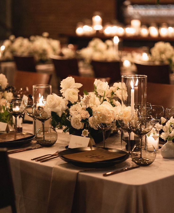 the table is set with white flowers, candles and place settings for an elegant dinner