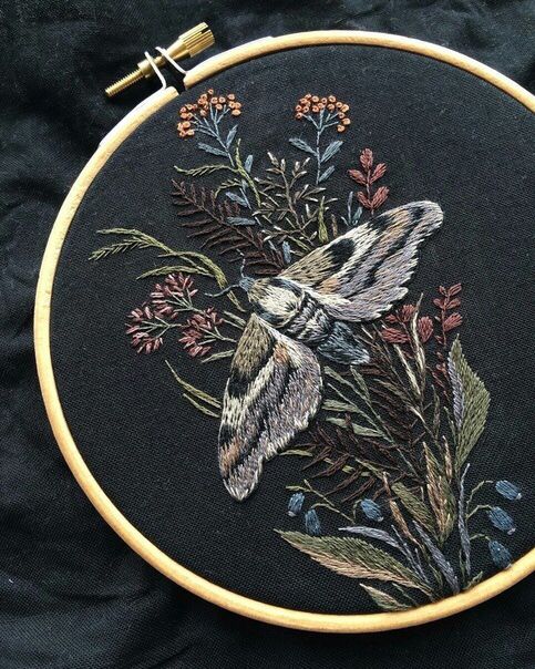 a close up of a embroidery on a black cloth with flowers and a bird in it