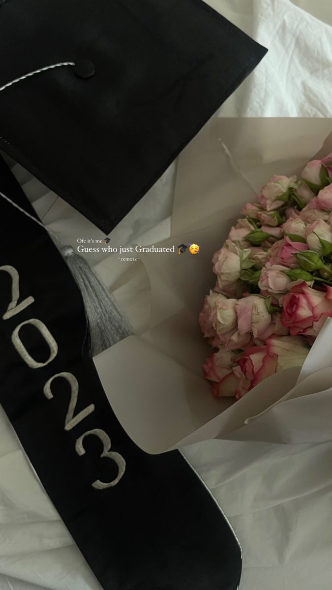 a bouquet of flowers and a graduation cap on top of a white sheet with black lettering