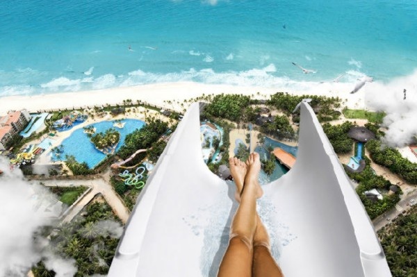 an aerial view of a person laying in a water slide at the edge of a beach