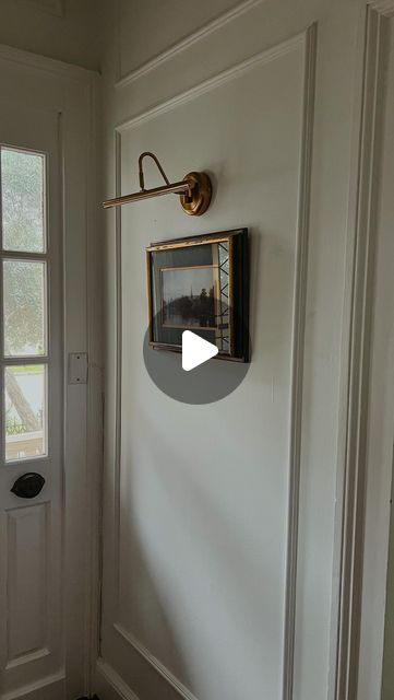 a white door with a framed picture hanging on it's side and a window in the background