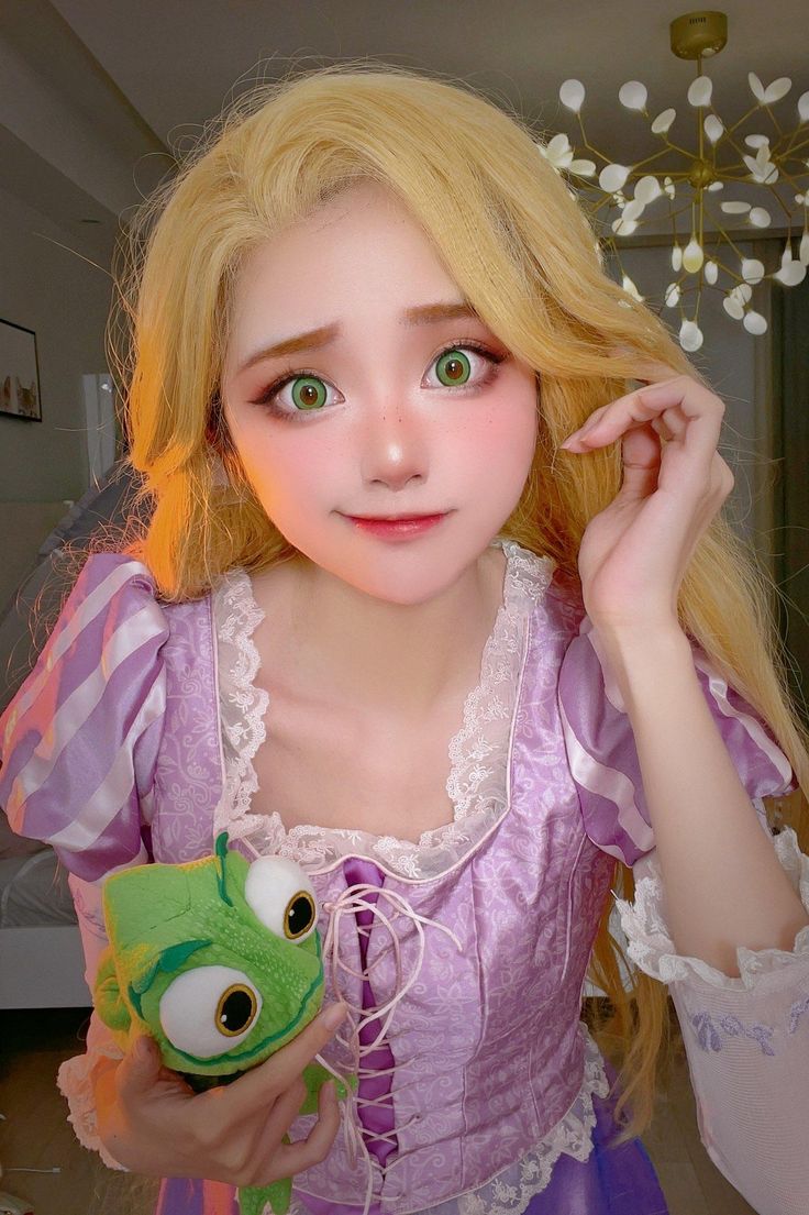 a doll with blonde hair and green eyes holding a frog