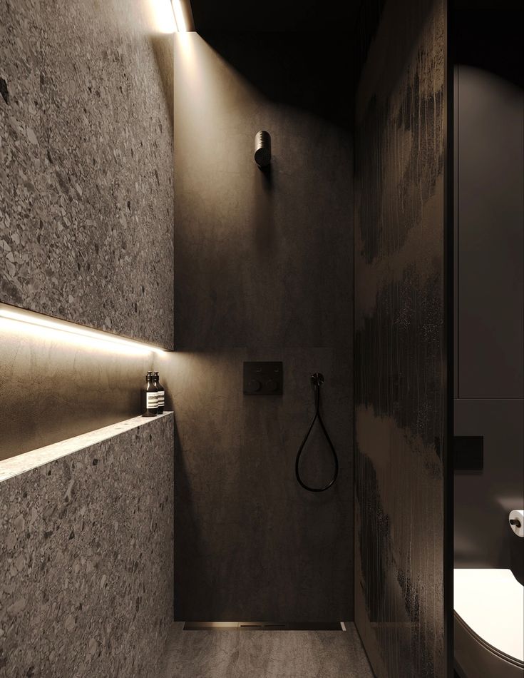 a bathroom with a shower, toilet and lights on the wall next to each other