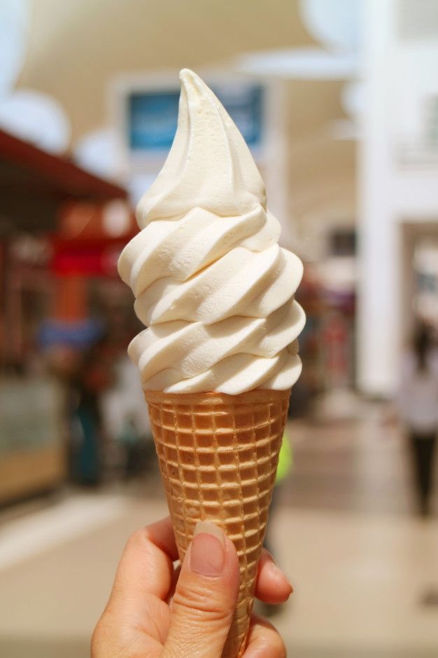 a hand holding an ice cream cone in a mall