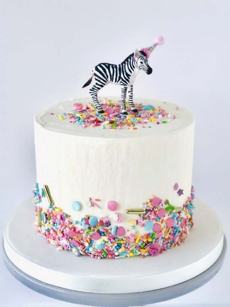 a white cake with sprinkles and a zebra figurine on top