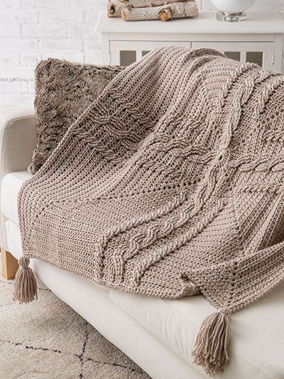 a white couch with a knitted blanket on it and the text, celtic cross cable throw crochet pattern