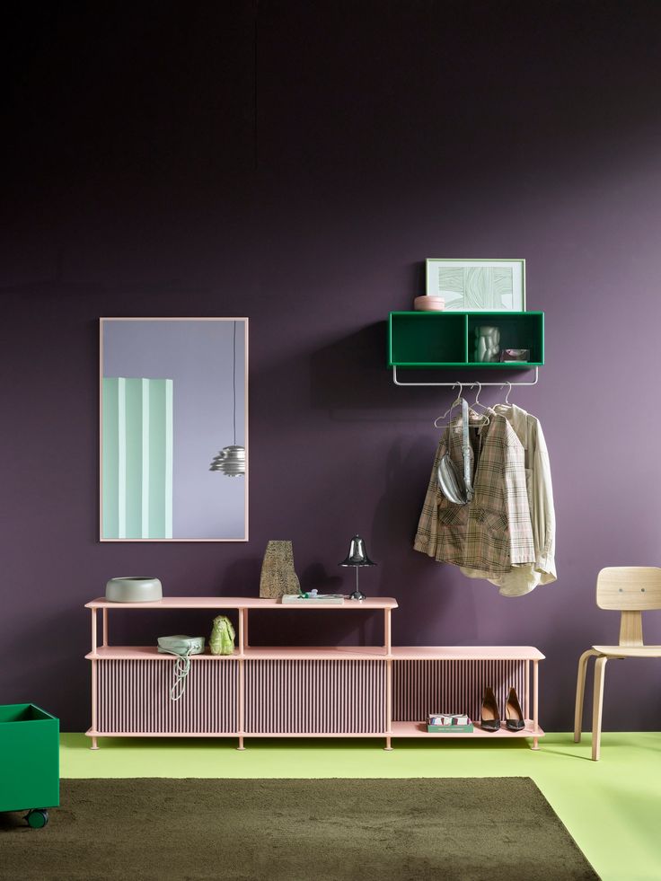 a room with purple walls, green shelves and a mirror on the wall next to a chair