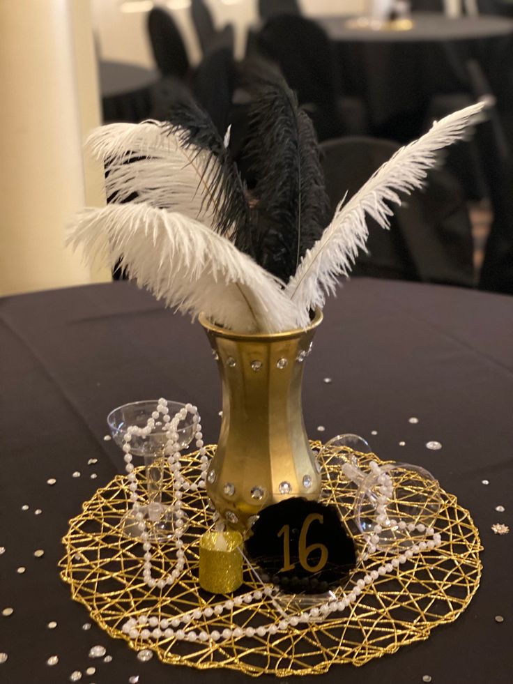 there is a vase with feathers in it on top of a table at a party