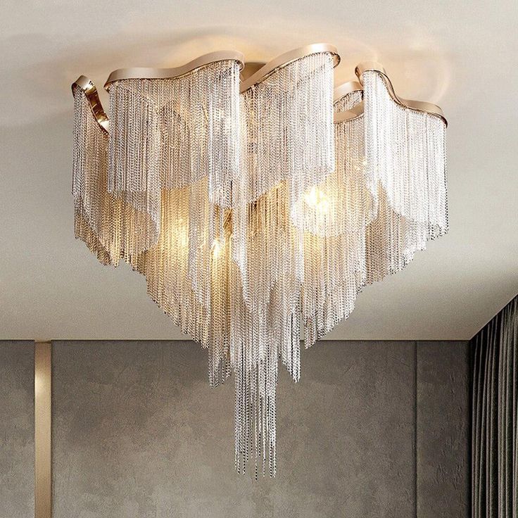 a chandelier hanging from the ceiling in a room with grey walls and curtains