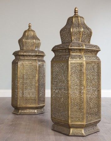 two large metal containers sitting next to each other on a wooden floor in front of a gray wall