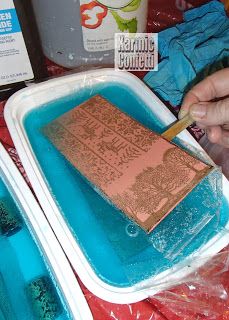 a person is using a brush to paint the inside of a container with blue liquid