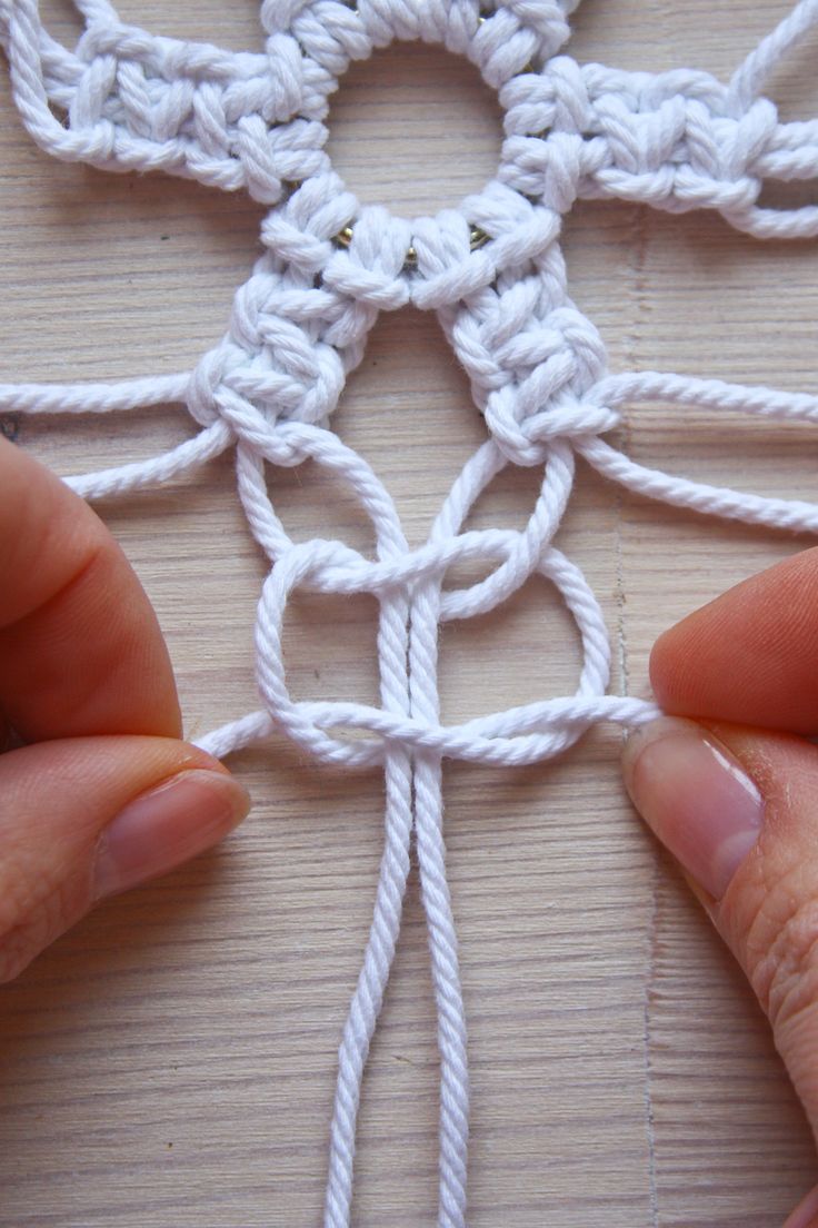 two hands are working on a crochet piece