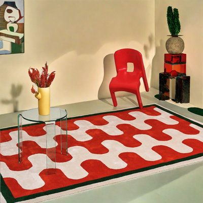 a red chair sitting on top of a rug next to a table