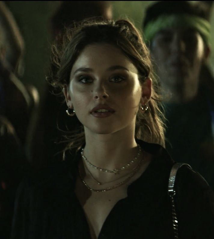 a woman standing in front of a group of people wearing pearls on her necklaces