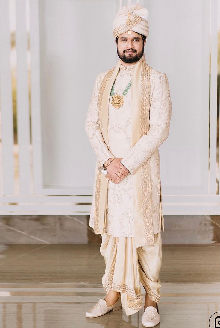 a man in a white and gold outfit standing on the floor with his hands behind his back