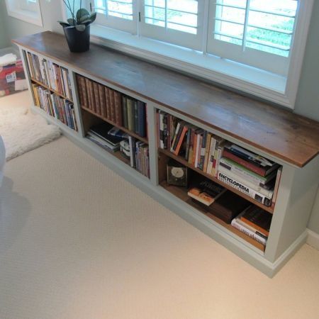 a bookshelf in the corner of a room with two windows and a couch