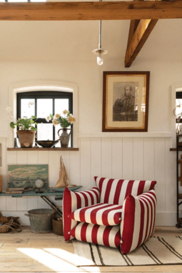 a living room with striped chairs and pictures hanging on the wall above it's windows