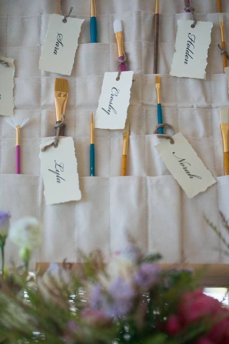 there are many toothbrushes hanging on the wall with name tags attached to them