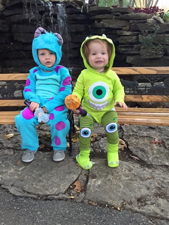 two young children dressed in costumes sitting on a bench next to a waterfall and water fall