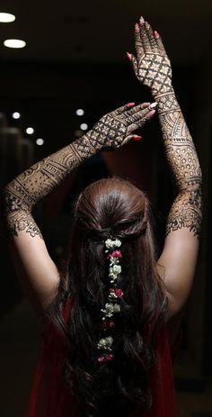 a woman with henna tattoos on her arms and hands, holding up her hand