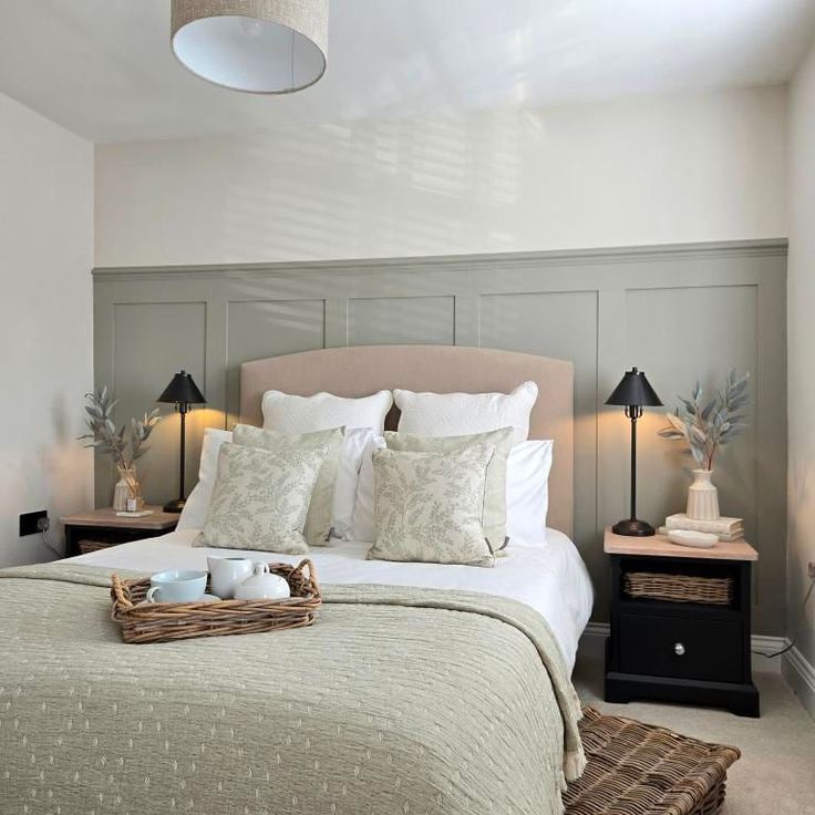 a bed with pillows and blankets in a bedroom next to two lamps on either side of the bed