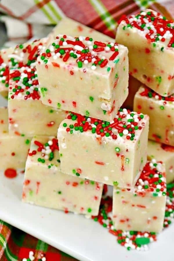 white chocolate fudges with sprinkles on a christmas table cloth and plaid napkin