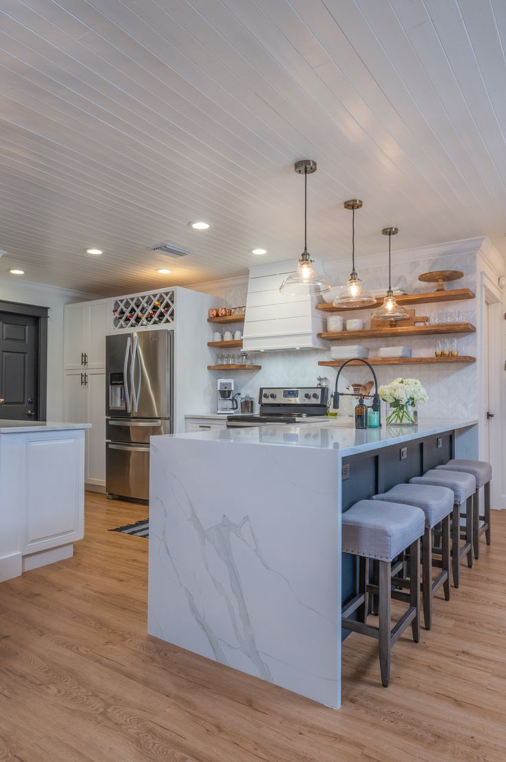 a kitchen with an island and several stools in front of the countertop area