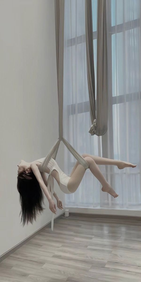 a woman is suspended upside down in the air with her legs stretched out and feet spread wide