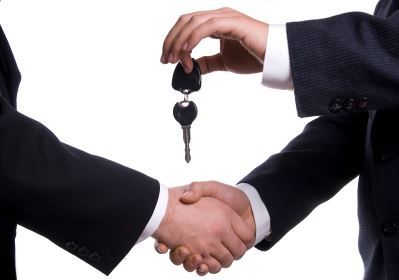 two people shaking hands with a key in their hand