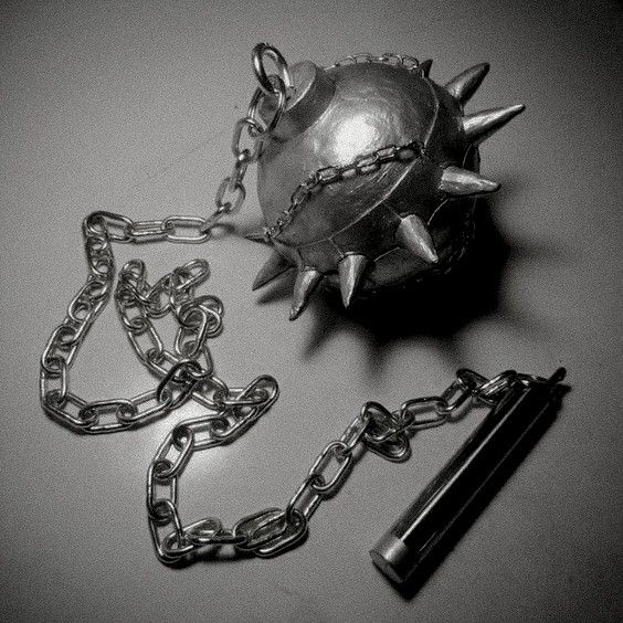 a metal ball with spikes and chains attached to it on top of a white surface