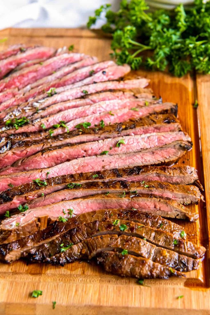 steak sliced up on a cutting board with parsley