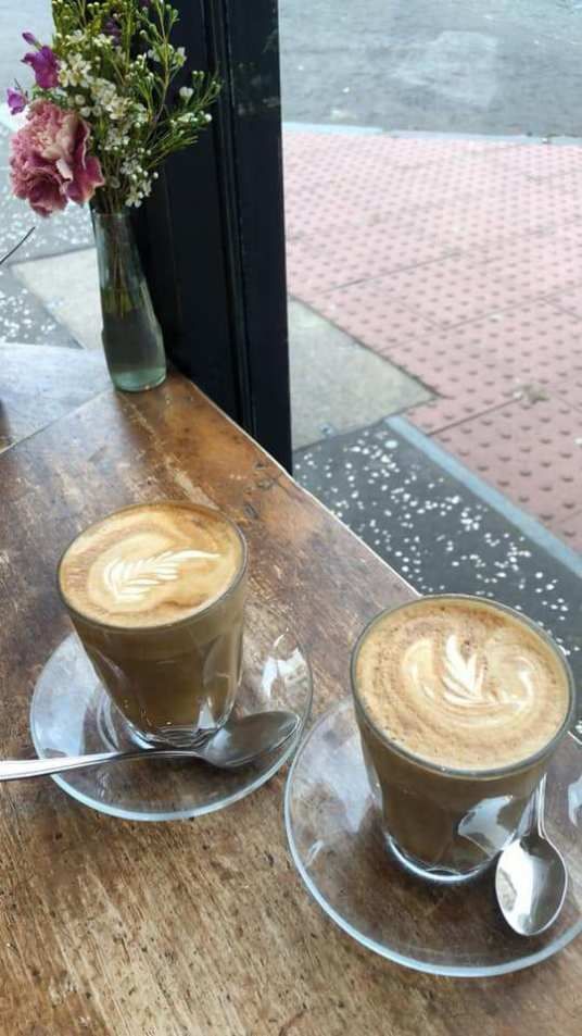 two cups of coffee sitting on top of a wooden table